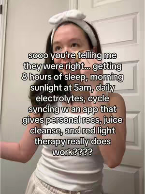 A woman with long, dark hair, wearing a white headband and a white tank top, stands in a bathroom with a white door and a mirror. Text overlays the image.