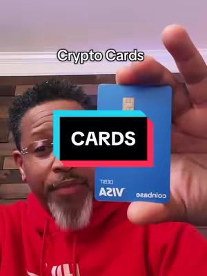 Image shows a person holding a blue credit card with the text 'CARDS' overlaid. The person is a man with glasses and a beard, wearing a red hoodie. The background appears to be a neutral wall.