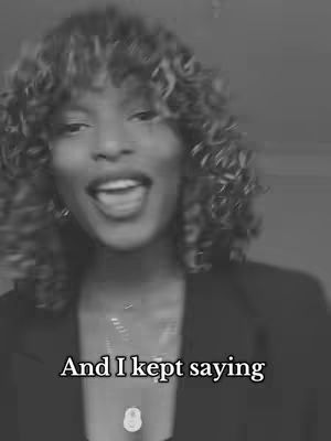 A grayscale image of a woman with curly hair, smiling with her mouth open, wearing a necklace. Text overlay reads 'And I kept saying'.