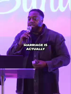 A man in a dark jacket stands in front of a microphone, with the text overlayed. The background is a soft, purple hue.