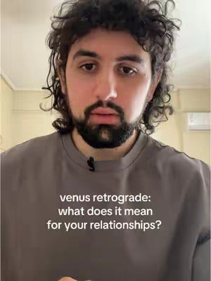 A man with dark curly hair and a beard looks directly at the camera. He wears a gray t-shirt, and the background is slightly blurred. Text overlayed on the image reads, "venus retrograde: what does it mean for your relationships?"