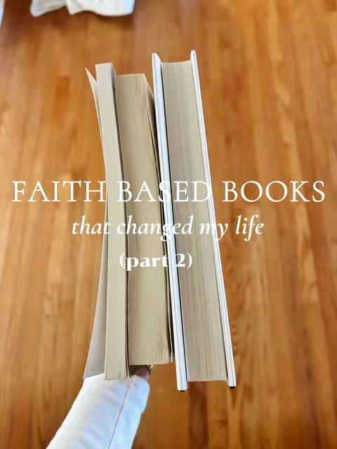 The image shows two books being held up, likely by a person out of frame. The books are thick, with beige covers and white spines, suggesting they are hardcover. They are positioned at an angle, creating depth. The background is a warm-toned wooden floor.