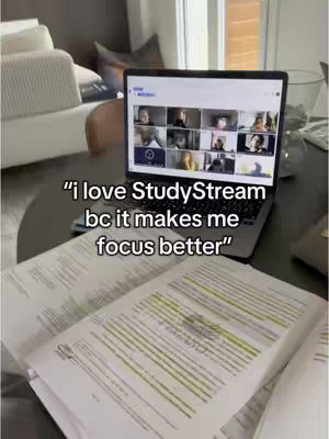 A laptop sits on a table with the screen displaying a group video call. Open books with highlighted text are in front of the laptop. The background shows pieces of a couch and a window.