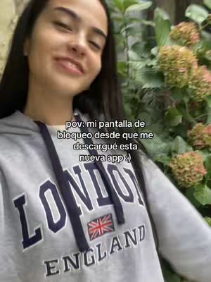 A young woman with long dark hair smiles towards the camera. She wears a gray hoodie with 'LONDON ENGLAND' printed on the front. Behind her, foliage provides a natural backdrop, and text overlays on the image.