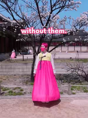 The cover image shows a person wearing a Korean traditional dress standing under a tree with pink blossoms. The person is facing the camera and wearing a red face mask. The background shows a traditional building and a clear sky. The text overlay says "without them."