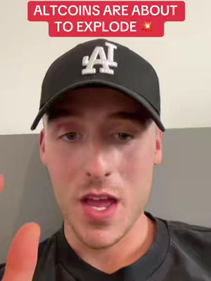 A young man wearing a black baseball cap with a white 'A' logo is speaking directly to the camera. A red banner at the top reads, 'ALTCOINS ARE ABOUT TO EXPLODE'. The background appears to be a simple wall, and the overall composition is a close-up shot focusing on the man's face.