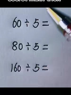A white surface with handwritten math equations. A pen is visible in the upper right corner. Text appears in a black, handwritten font, presenting math problems involving division by 5.