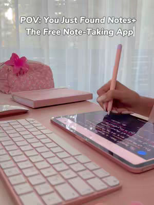 The image showcases a well-lit desk setting bathed in soft pink hues. A hand holding a pink stylus is poised over a tablet, actively taking notes. A white, light-colored keyboard sits in front of the tablet. Decorative items like a pink flower, and a pink pencil case add to the feminine aesthetic. The overall composition suggests a study or work-from-home environment.