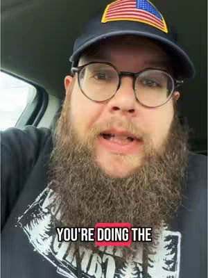 A close-up shot of a man in a car, wearing a baseball cap with an American flag patch, round glasses, and a thick beard. Text overlay in a red box reads, 'YOU'RE DOING THE'. The background shows the inside of a car.