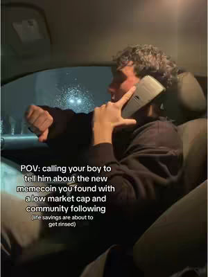 A man is seated in the front seat of the car, holding a phone to his ear. The scene is set at night. The interior lights are on, a city is seen outside the window.