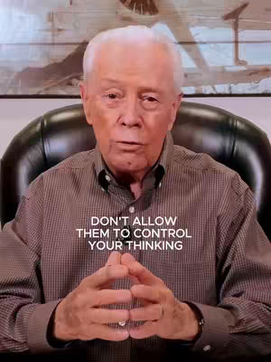 An elderly man with white hair is seated in a black leather chair. He's wearing a dark shirt and looking directly at the camera, with his hands clasped in front. Text on the image reads: DON'T ALLOW THEM TO CONTROL YOUR THINKING.