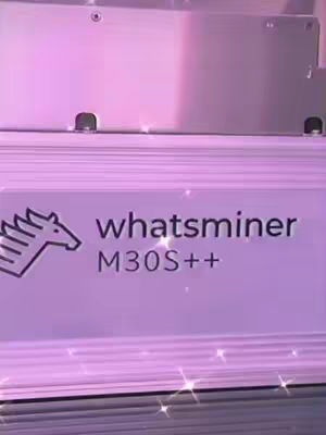 The image shows a close-up of a Whatsminer M30S++ mining machine. The machine is primarily silver with a logo featuring a stylized horse head. The text "whatsminer M30S++" is prominently displayed in a purple box with the logo on the left. The background is a gradient of pink, and there are sparkling effects scattered throughout.
