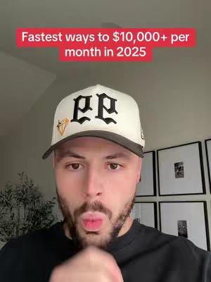 A man with a beard and a baseball cap is centered in this selfie-style shot. Above him, in a red banner, is the text overlay 'Fastest ways to $10,000+ per month in 2025'. The man is looking directly at the camera, with his lips pursed as if he is about to blow a kiss. The background is a few framed pictures.