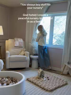 A person stands by a window in a nursery, looking out. The room is filled with neutral-toned furniture and decor, creating a peaceful atmosphere. Text overlays are added to the image.