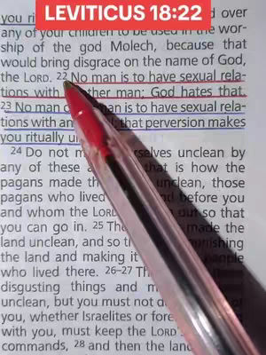 A close-up shot shows a pen pointing at a highlighted passage from the Bible, specifically Leviticus 18:22. The text is partially visible, and the pen's shadow adds depth.
