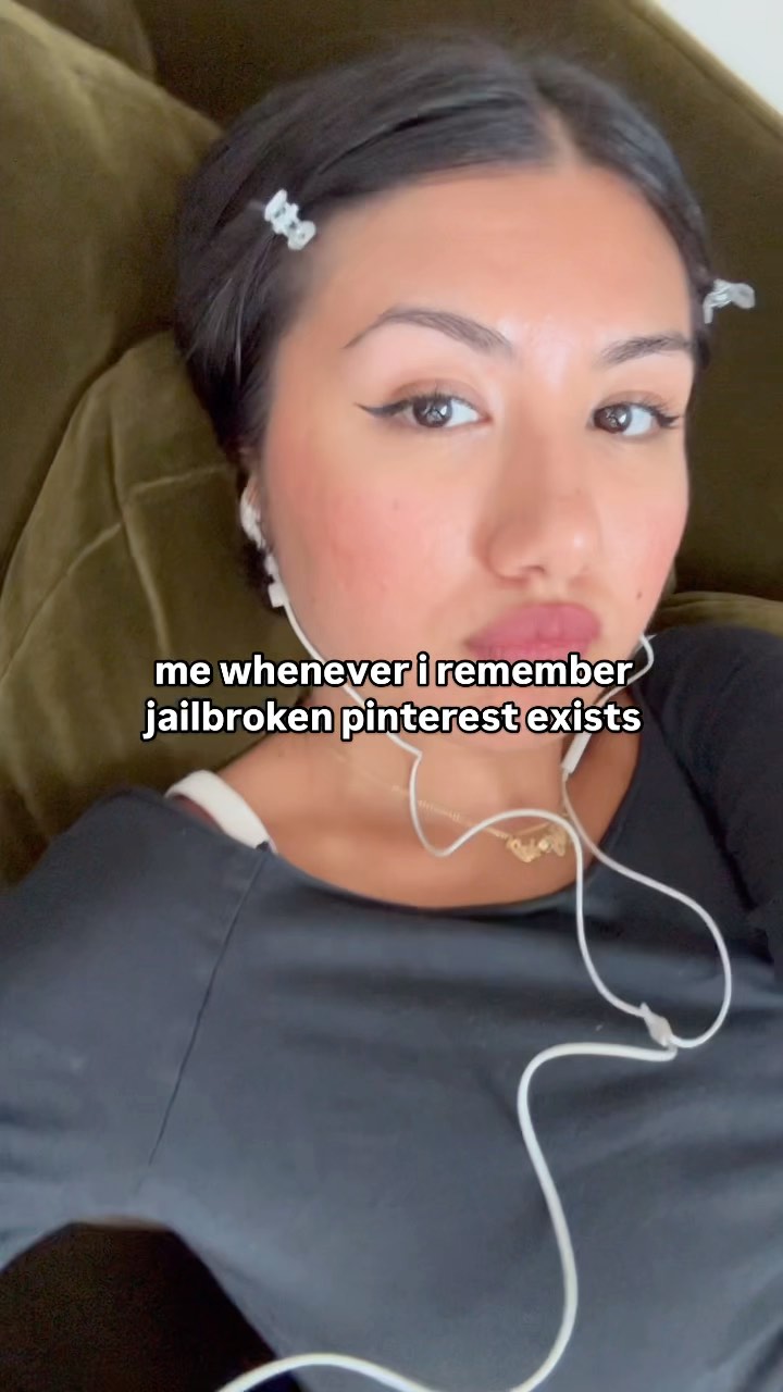 A selfie-style shot with a young woman lying on a green couch, her face filling most of the frame. She has dark hair, styled with small butterfly clips, and is wearing a black top. Text overlayed on the image reads, "me whenever i remember jailbroken pinterest exists."