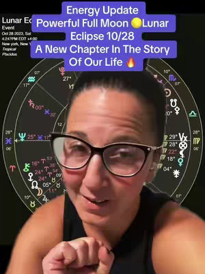 The cover image features a woman with dark hair and glasses, framed from the chest up. She is in front of a complex astrology chart. Text overlays at the top include "Energy Update", "Powerful Full Moon Lunar Eclipse 10/28," and "A New Chapter In The Story Of Our Life." The woman appears to be speaking to the camera.