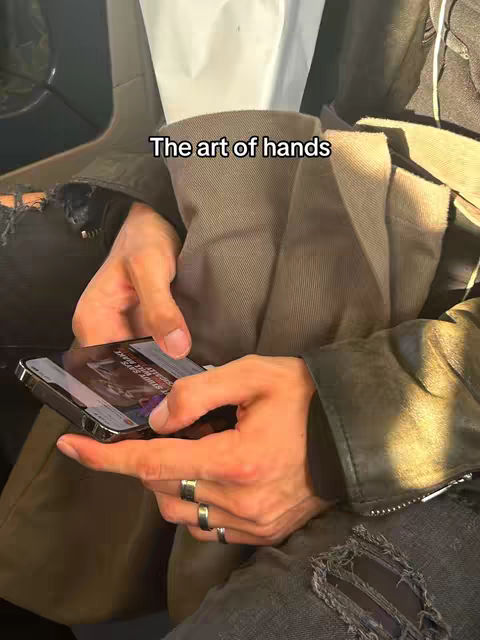 The cover image features a close-up of a person's hands holding a smartphone. The person is wearing rings on their fingers. The background features a neutral-toned jacket and denim jeans. The lighting appears to be natural and soft.