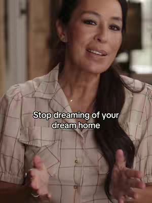 A woman with long dark hair is centered in the frame, posing indoors. She has fair skin, brown eyes, and a neutral facial expression. She is wearing a beige patterned button-down shirt. The background is blurred, but shows a glimpse of some wood furniture. Overlayed on the image is white text.