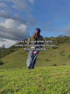 A woman stands on a grassy hillside facing away from the camera. She wears a blue beanie and a long, flowing dress. Text overlays the image, and the sky is a bright blue with scattered clouds.