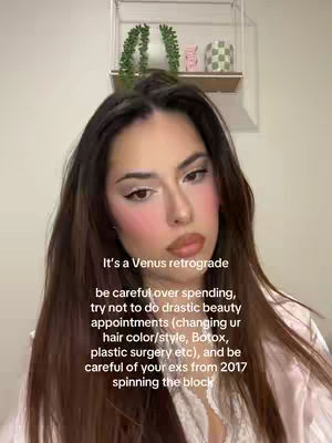 The cover image is a selfie of a woman with long brown hair and makeup. The background is blurred, but part of a shelf is visible with decorative items. Text overlayed on the image provides astrological guidance.