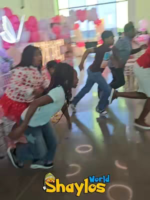 A group of children running toward the camera, some appearing to be part of a scavenger hunt. The background is slightly blurred, with colorful balloons visible, suggesting a party setting. The bottom right has a logo of a character.