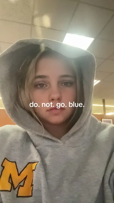 A close-up shot of a young woman wearing a gray hoodie, looking directly at the camera with a serious expression. The text overlay says 'do. not. go. blue.'