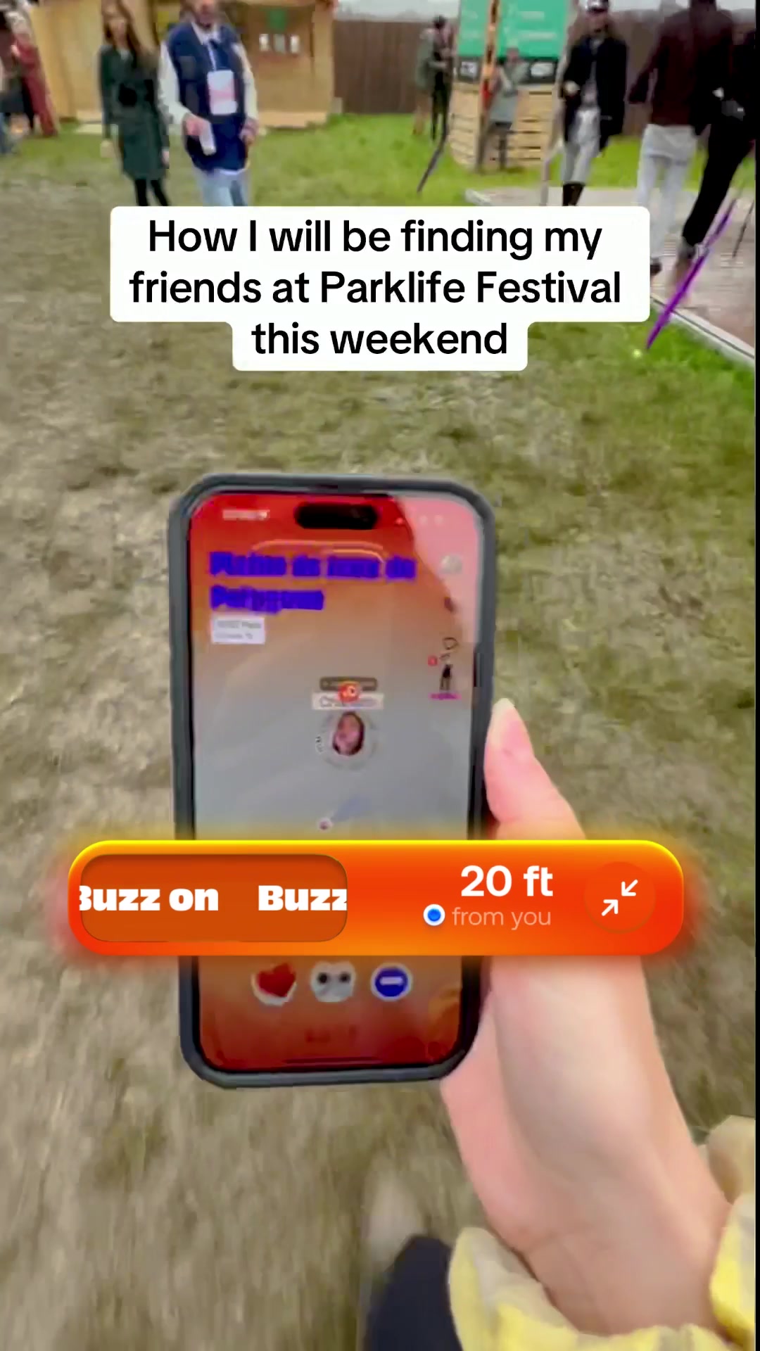 A person is holding a phone displaying an app interface with location data. On the screen, a map shows nearby users, with an icon labeled for the creator. Overlayed text indicates '20 ft from you'. The image shows an outdoor festival setting with crowds and tents in the background.
