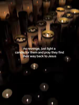 A low-angle shot shows numerous lit candles, both small and tall, arranged closely together. The focus is on the warm light emitted by the flames against a dark background. Text is overlaid on the image, conveying a message of faith and prayer.