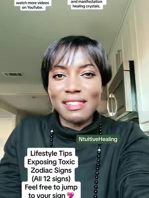 A medium shot features a woman with short black hair smiling at the camera. She is wearing a black turtleneck and a long beaded necklace. Text overlays appear in the bottom center of the frame, indicating the video's topic. The background includes a glimpse of a kitchen setting.