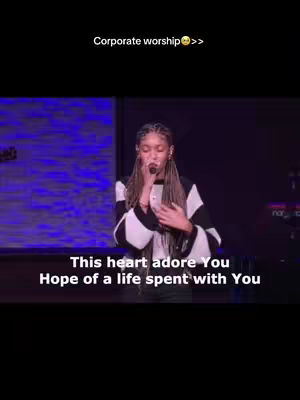 A woman is singing into a microphone on a stage. The image has overlaid text including song lyrics. The background has a blue and purple gradient. The woman is wearing a black and white striped top.