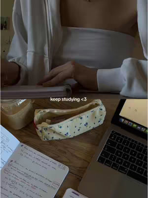 A workspace with a laptop, notebooks, and a pencil case is centered on a wooden surface, with the creator's hands visible as they work, topped with a text overlay inviting viewers to keep studying.