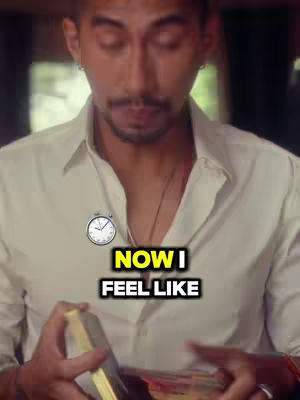 A man with facial hair, wearing a white shirt, holding tarot cards. Text overlayed says 'NOW I FEEL LIKE' with a clock icon.