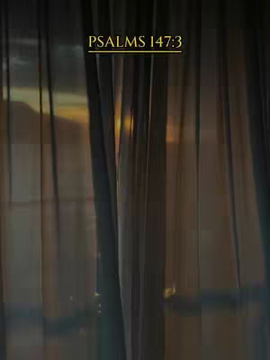 An image of a window with vertical curtains. Through the curtains, a sunrise or sunset is visible, casting a warm glow. The title 'PSALMS 147:3' is displayed at the top.
