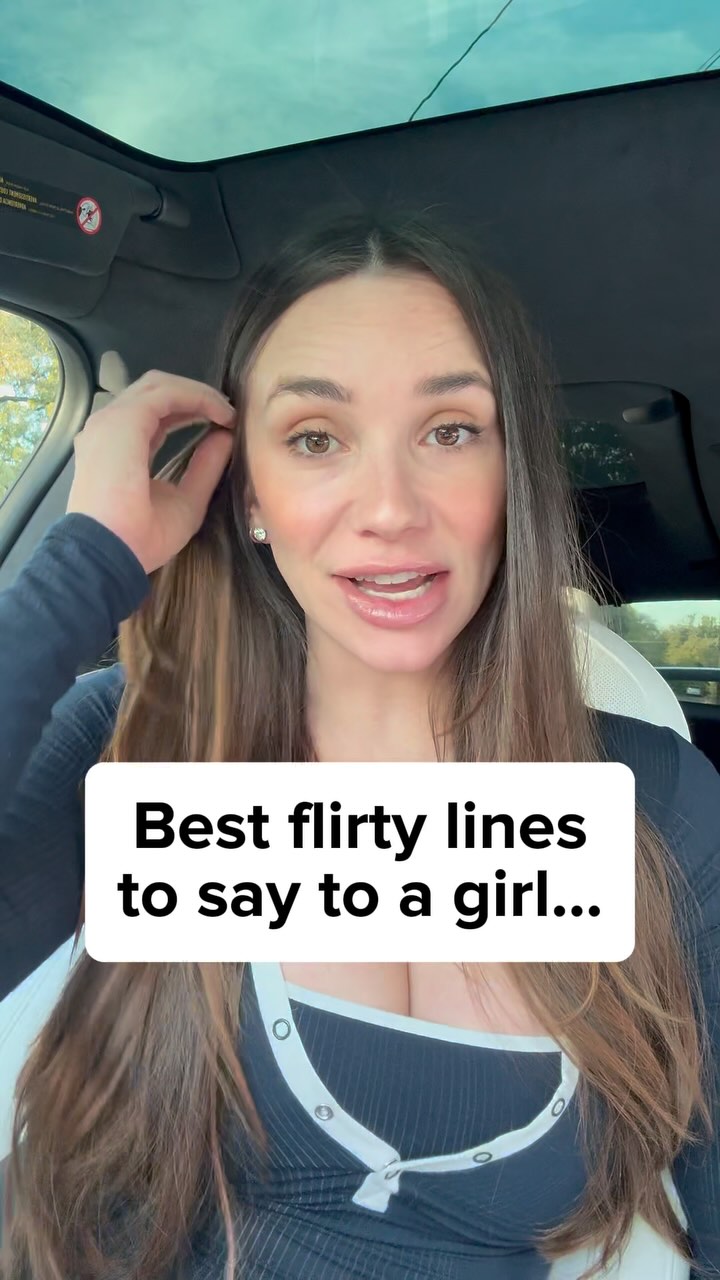 A woman is seated in a car, looking at the camera and speaking. She has long brown hair, and the focus is on her face and upper body. A white rectangular text box overlaid on the image reads, “Best flirty lines to say to a girl…”