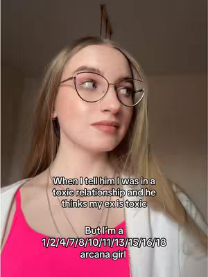 A selfie-style shot featuring a woman with blonde hair and glasses, looking slightly off-camera. The background is simple, suggesting an indoor setting. The woman is wearing a bright pink top and a white jacket. Text overlays appear below her, describing the video's premise.
