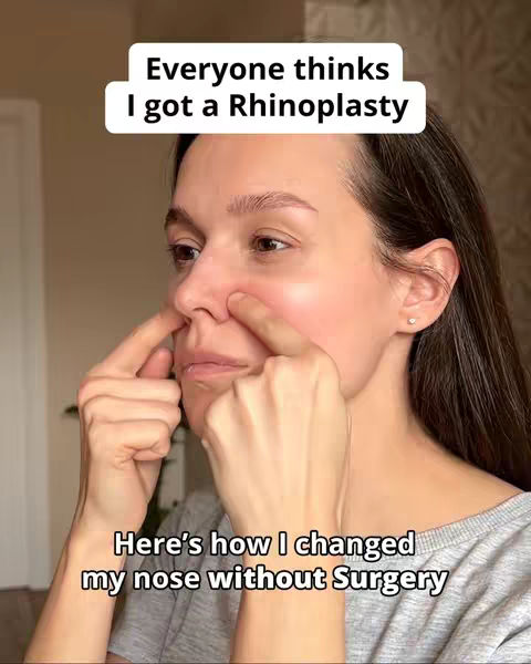 A woman with dark hair touches her nose with both index fingers, focusing on the bridge. Above is a white text box with the phrase 'Everyone thinks I got a Rhinoplasty.' Below, in a matching font, is a text box stating, 'Here's how I changed my nose without Surgery.' The background is blurred, with neutral tones.