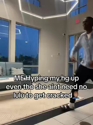 A man is filmed walking towards the right, indoors, looking at the camera. The background is a bright, modern open space with large windows. Text overlays the image.