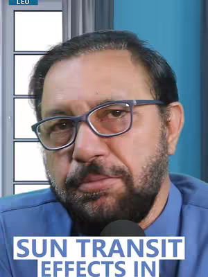 A man with glasses and a beard is centered in the frame, with a blue shirt.