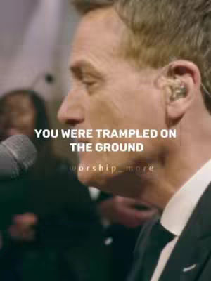 The image shows a close-up of a man speaking into a microphone, with a blurred background. Text overlays the image.