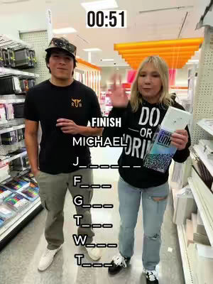 Two people standing in a store aisle, a man on the left and a woman on the right. The man wears a black shirt and a baseball cap. The woman is holding a product and waving, with a "Finish" text overlay next to her. The background shows store shelves and lighting.