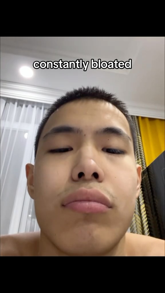 A selfie-style shot focusing on a person's face. The person has short dark hair, slightly closed eyes, and full lips. The overall image is framed closely, emphasizing the facial features against a blurred background.
