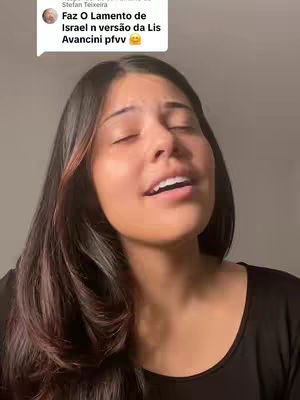 A close-up of a young woman with long, dark hair, a subtle smile, and her eyes closed as if singing. A speech bubble with text is in the upper left, typical for a video response.