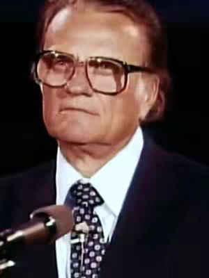 The cover image features a portrait of Billy Graham, a man with light skin, wearing thick-rimmed glasses and a dark suit with a patterned tie. He is looking slightly down and to his left. A microphone is visible in front of him.