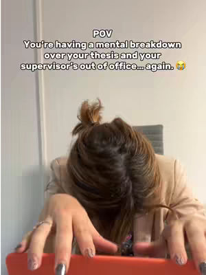 The image shows a person, likely a woman, with her head resting on her arms, which are placed on a table or desk. Her hair is pulled up in a messy bun. The top of the frame has a text overlay.