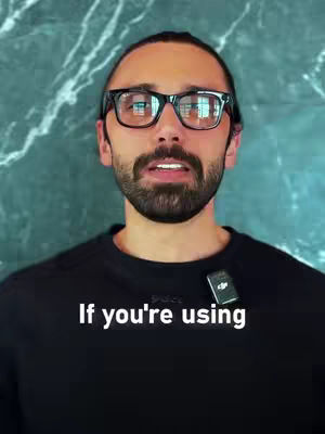 A man with a beard and glasses is centered in the frame. He's wearing a black shirt. Below, overlaid text reads, 'If you're using.' The backdrop is a textured, dark green surface.