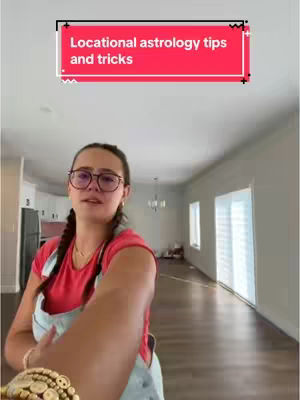 A woman with glasses and a red shirt is in an empty room while the camera holds up her arm. A red banner says "Locational astrology tips and tricks".