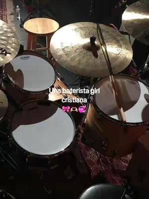 A close-up shot of a drum set from a top-down angle. The image shows a drum set with multiple drums, cymbals, and drumsticks. The text overlayed on the image reads "Una baterista girl cristiana" accompanied by some emojis.