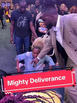 A crowd of people in a church setting. In the foreground, a person is on their knees with their hands by their side and multiple people around them, with one of the men placing a hand on the person. Text that says "Mighty Deliverance" is on the image with a red box.
