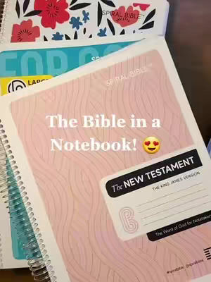The cover image features a close-up shot of a spiral-bound notebook, labeled as 'The New Testament' of the King James Version Bible. The notebook has a light pink cover with a wave-like pattern and overlayed with text in white. Below the notebook, there are several other spiraled notebooks, one with a turquoise cover, one white with flowers, and parts others and some of them have yellow sticky notes. These are stacked or partially visible in the background.